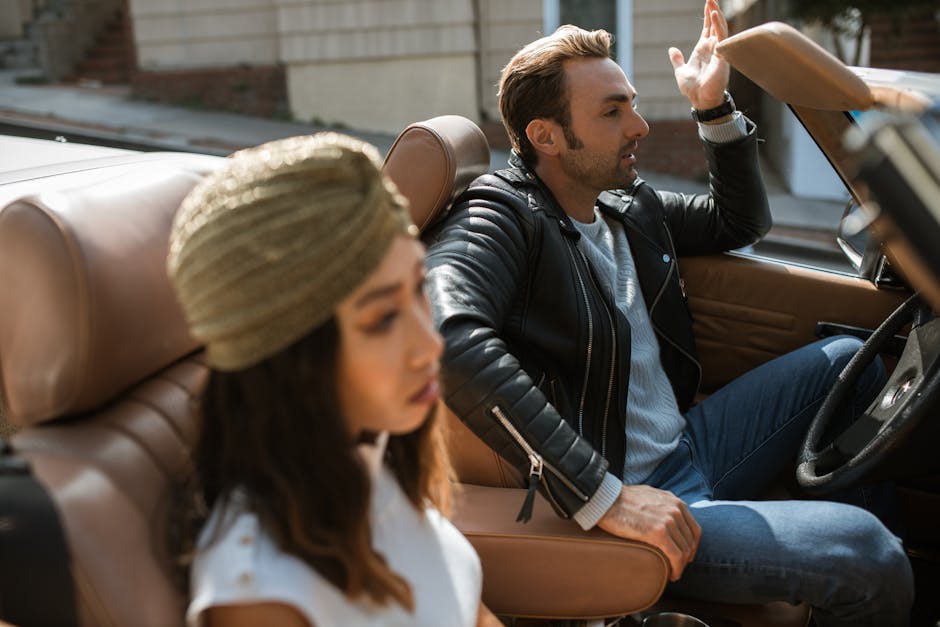 A couple argues in a stylish convertible, tension evident in their expressions.