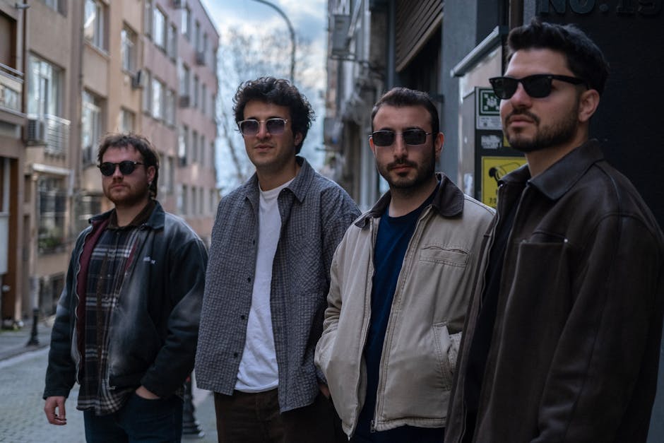 Four men wearing sunglasses pose casually in a narrow street in Istanbul, showcasing a stylish urban vibe.