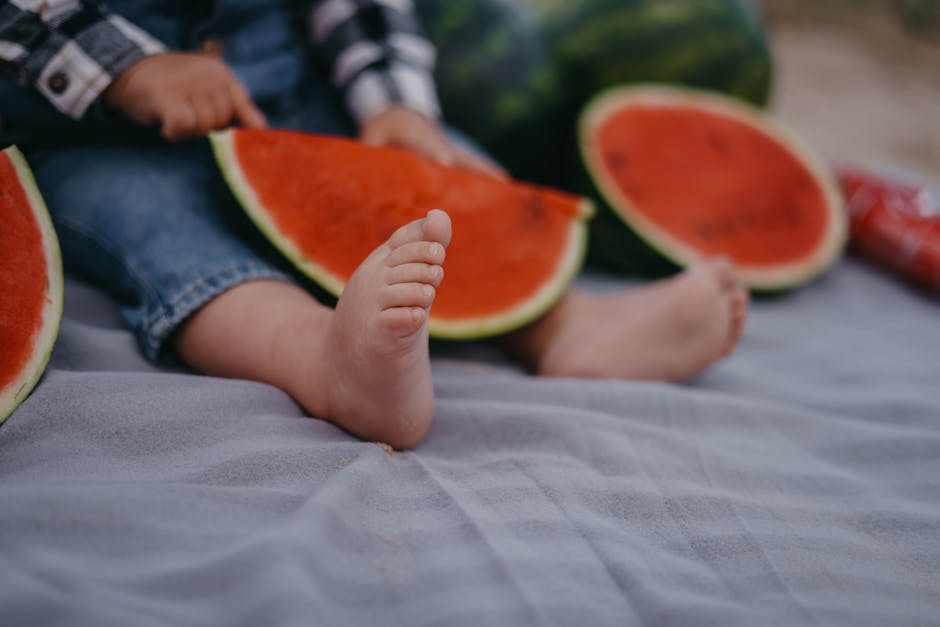 Adorable scene of a baby sitting with watermelon slices on a warm summer day.