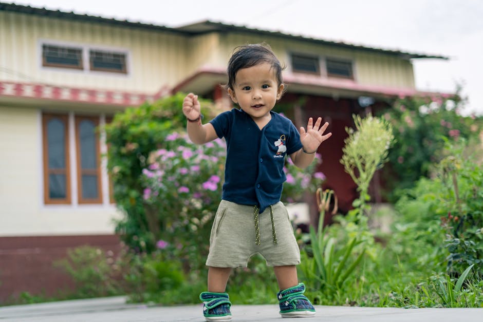 Cute toddler joyfully exploring a garden outdoors, surrounded by vibrant greenery and flowers.