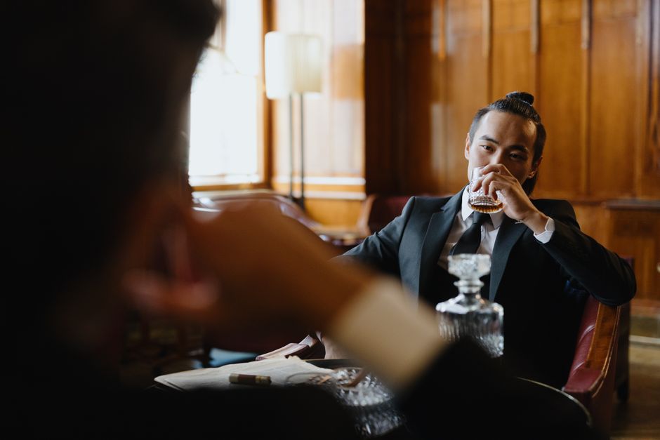 Sophisticated man in a suit enjoys a drink in a luxurious lounge.