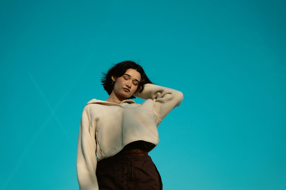 Portrait of a serene woman with closed eyes posing against a vibrant turquoise background.