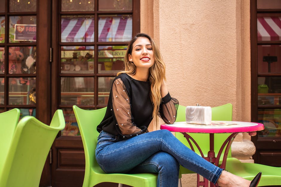 Stylish woman smiling at a vibrant outdoor cafe, enjoying a sunny day.
