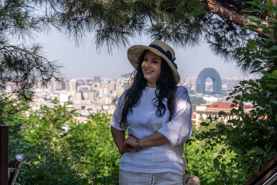 A woman in a summer hat enjoys a scenic view of Baku's skyline on a sunny day.