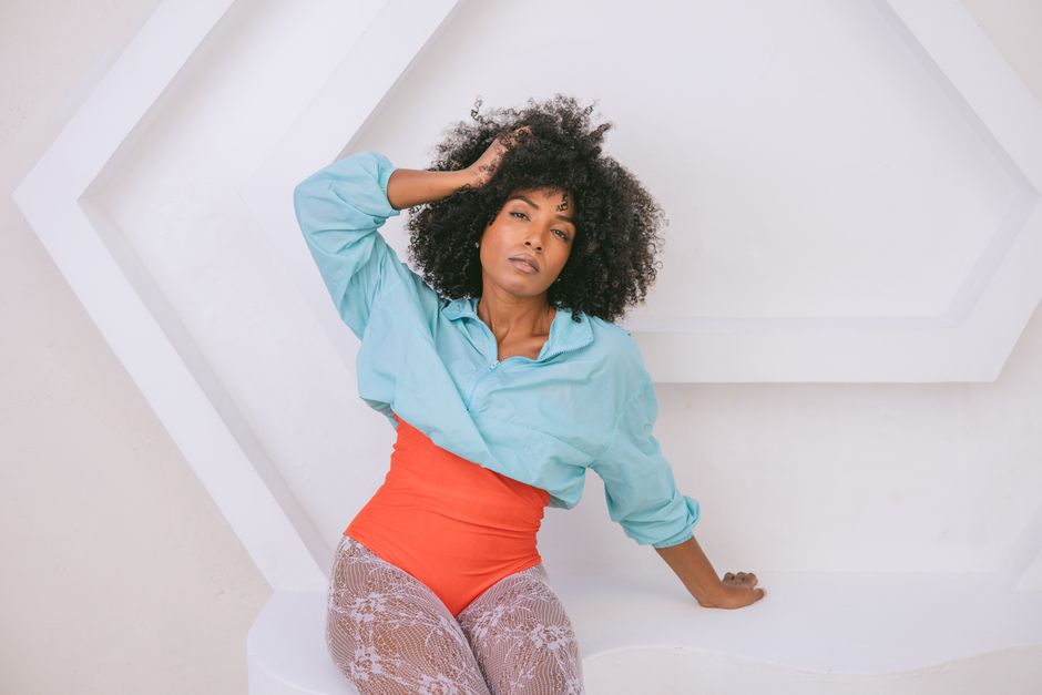 Elegant portrait of a woman in vibrant clothing against geometric backdrop.