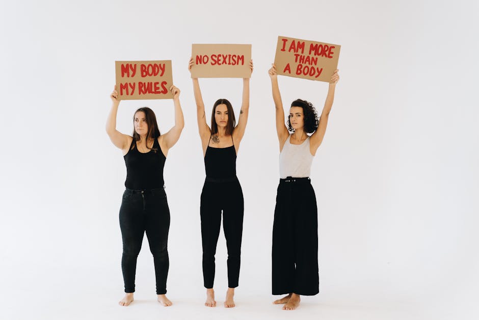 Three women holding feminist placards against sexism in a studio setting, promoting empowerment.