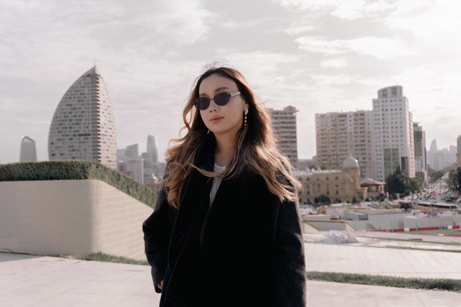 Stylish woman in sunglasses exploring a cityscape with modern and classic architecture.