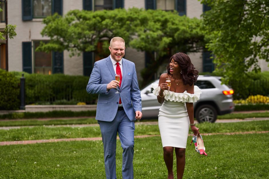 A happy couple enjoying a celebration in a park setting, sharing drinks and laughter.