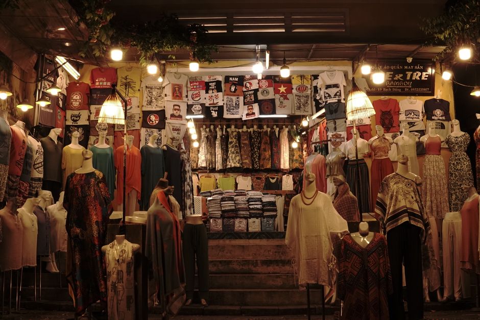 Vibrant clothing display at a Vietnamese night market featuring various dresses, shirts, and mannequins.