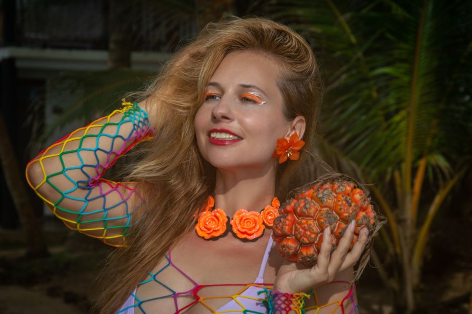 Vibrant portrait of a woman holding tropical fruit, surrounded by palm trees.