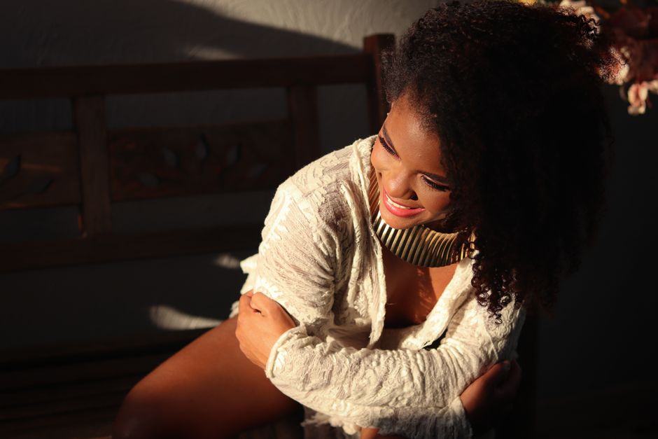 Elegant woman in a sunlit room with a joyful expression and stylish attire.