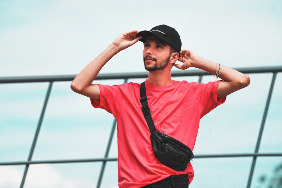 Stylish man in pink shirt with a fanny pack posing outdoors against a modern backdrop.