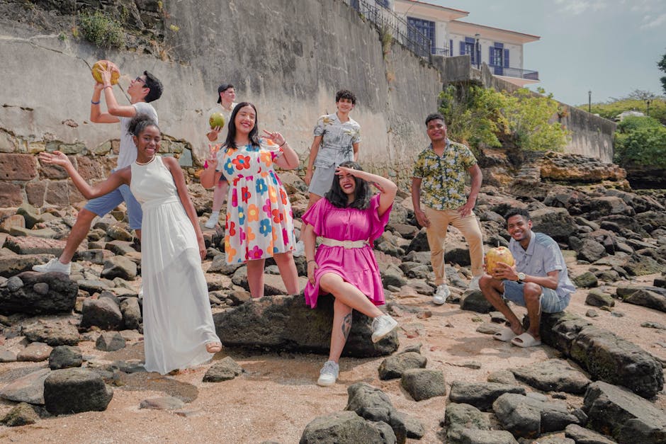 Vibrant group of friends posing and smiling on rocky summer beach.