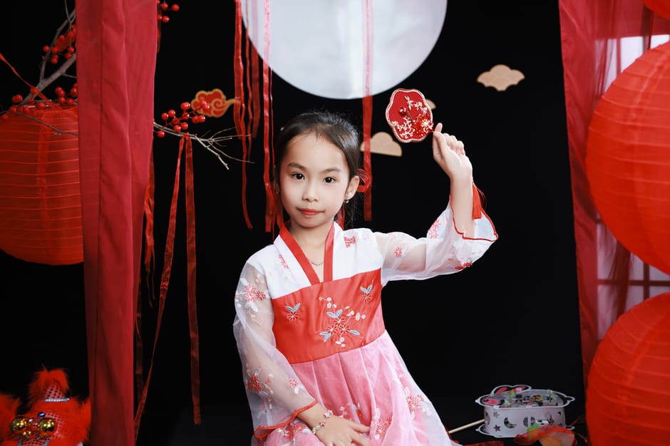 A young girl in traditional attire celebrating the Lunar New Year with festive red decorations.