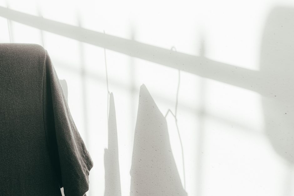 Minimalist photo of hanging clothes casting shadows on a sunlit wall