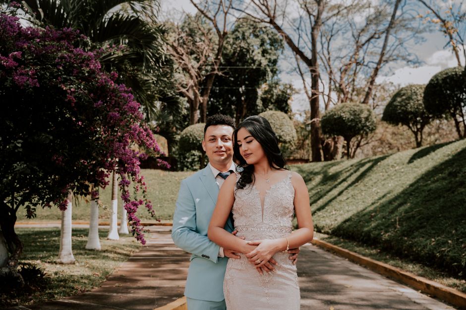 A stylish couple poses together in a beautiful park setting, capturing elegance and love.