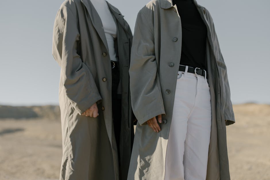 Two fashionable women wearing trench coats in a desert landscape, exuding minimalist style.